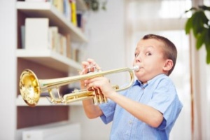Little boy is playing the trumpet at home